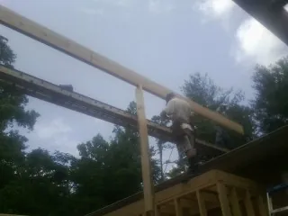Carpenter setting a ridge beam over a new addition frame — Ice Dam Removal by Roofing Brothers in Hubert