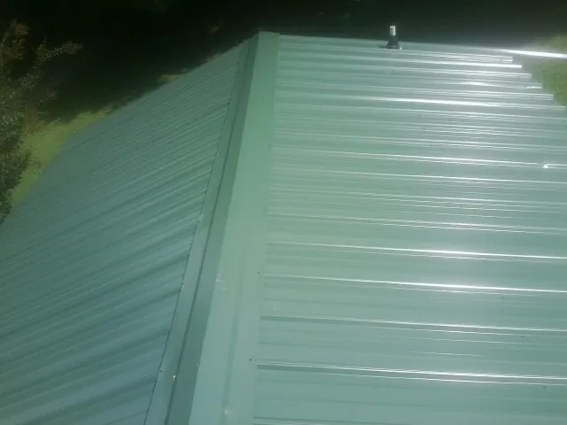 New green metal panels meeting at the ridge of a roof — Flat Roof Repair work by our crew in Hubert