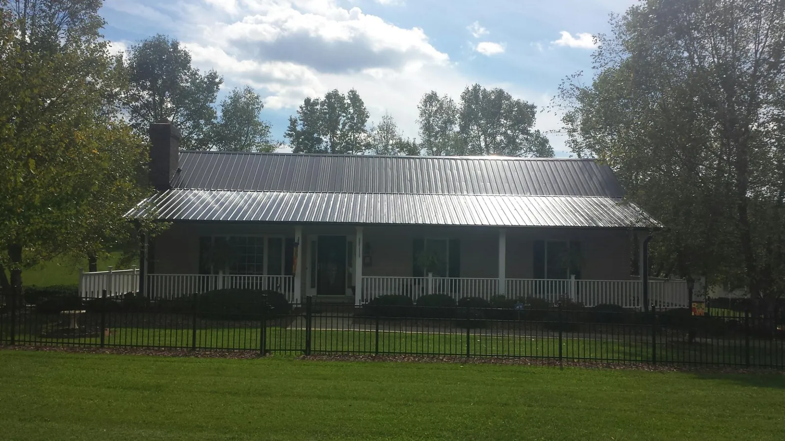 Gray metal roof on a brick ranch with a full width front porch — Gutter Guard Installation work by our crew in Hubert