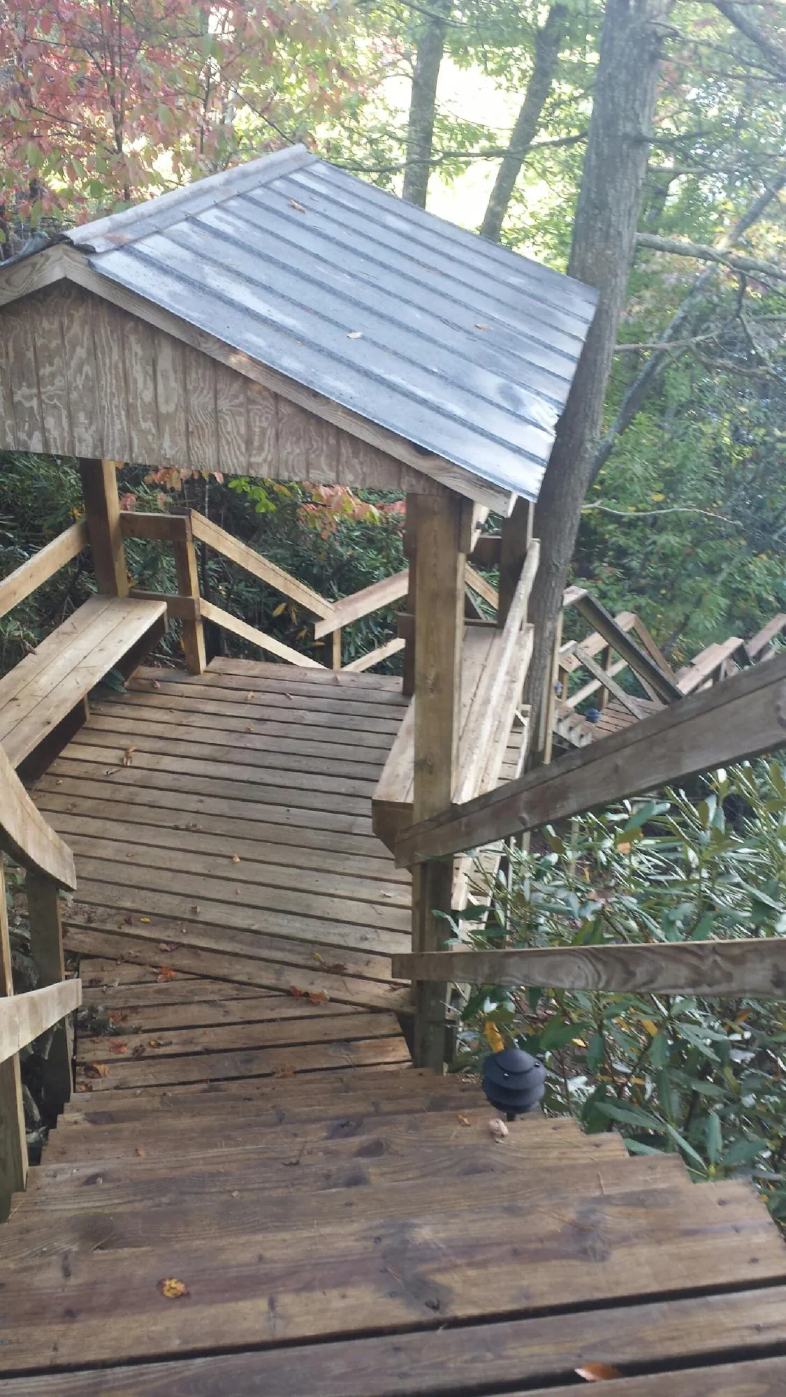 Metal roofed shelter over wooden steps on a wooded walkway — Skylight Repair & Installation work by our crew in Hubert