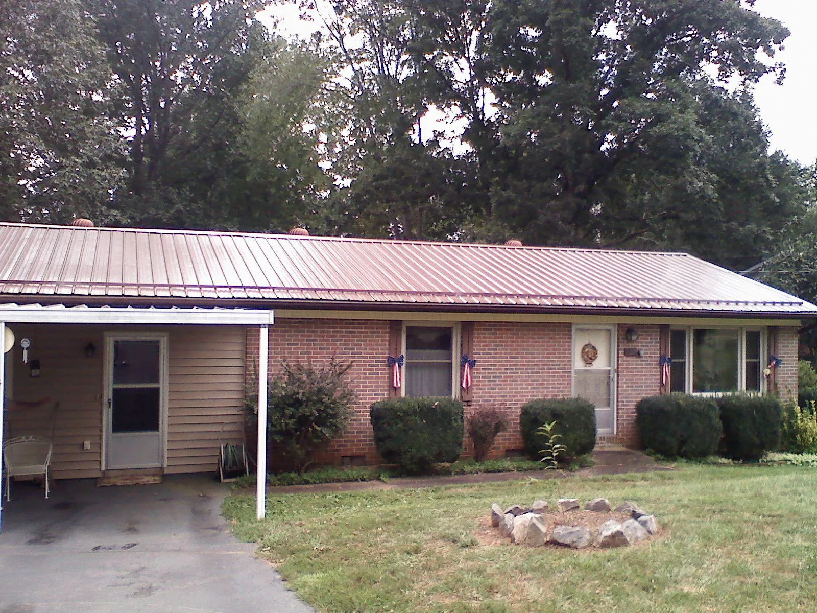 Bronze metal roof and carport on a brick ranch home — Roof Repair work by our crew in Hubert