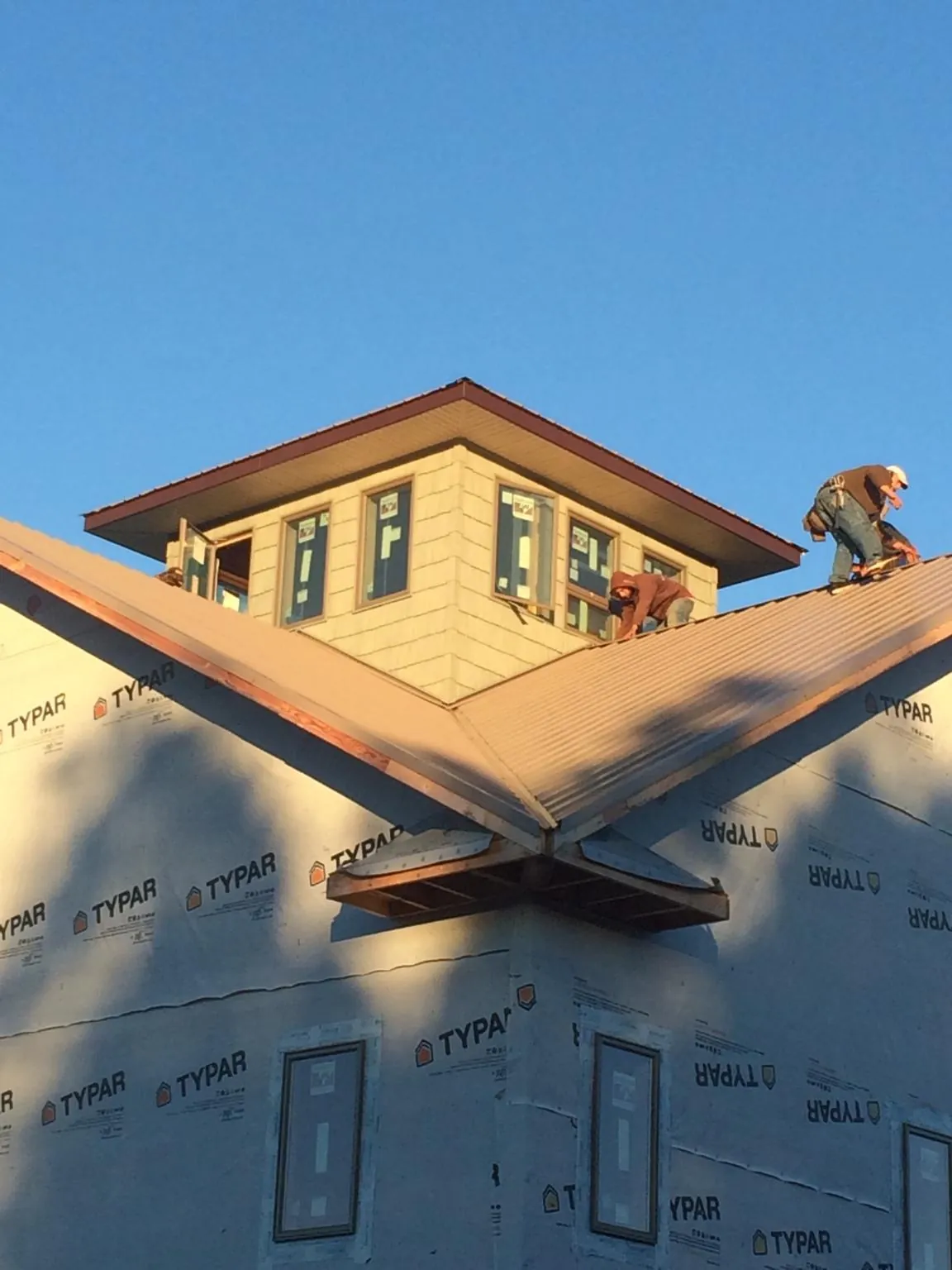 Roofers working around a rooftop cupola on a new metal roof at sunset — Roof Waterproofing in Hubert by Roofing Brothers